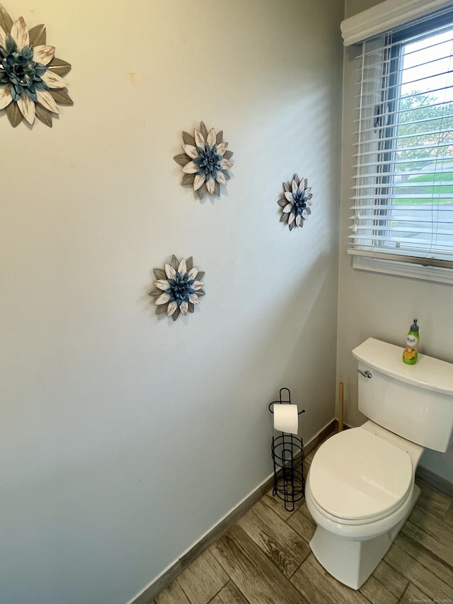 bathroom featuring baseboards, wood finished floors, and toilet