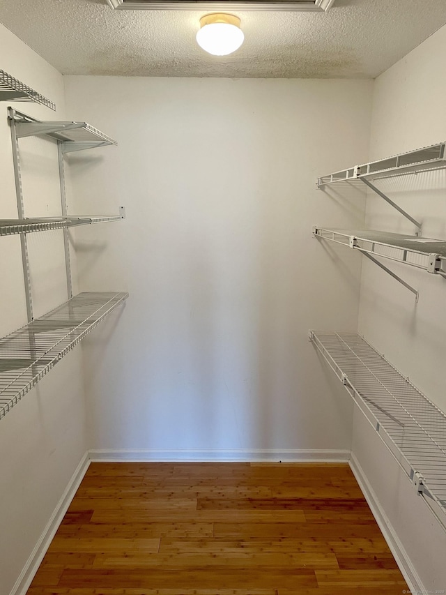 walk in closet with wood finished floors