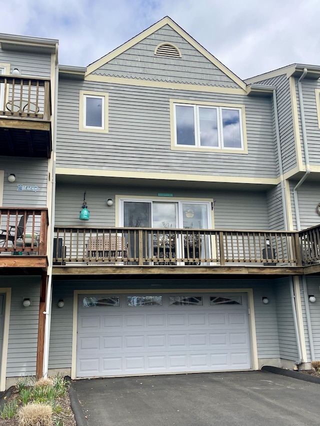 back of house featuring a garage, a balcony, and aphalt driveway