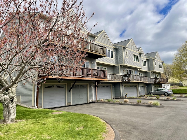 view of front facade featuring a garage, a front lawn, a balcony, and driveway
