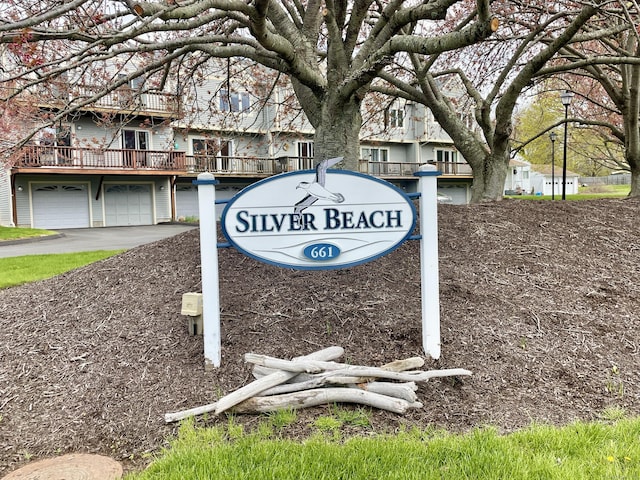 community sign with an attached garage and aphalt driveway