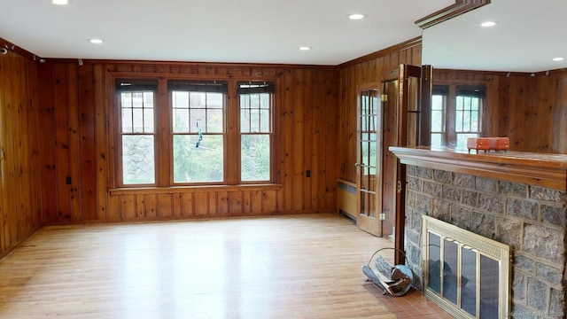 85 Hillcrest Ter, Meriden, CT 06450 - unfurnished living room with wood walls, light wood-style flooring, radiator, recessed lighting, and a stone fireplace