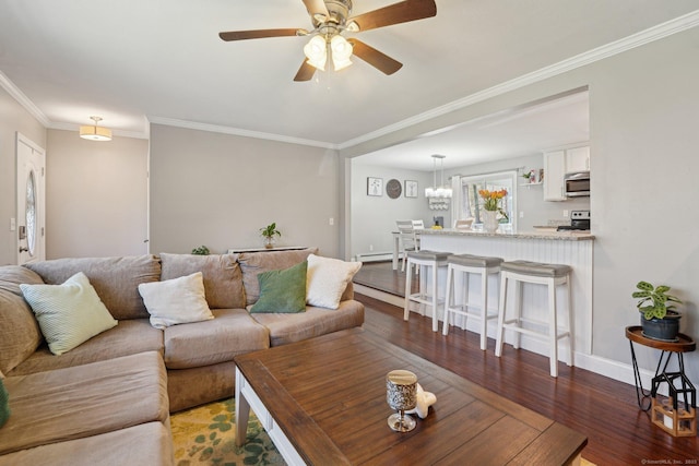 living area featuring wood finished floors, crown molding, baseboards, ceiling fan, and a baseboard heating unit