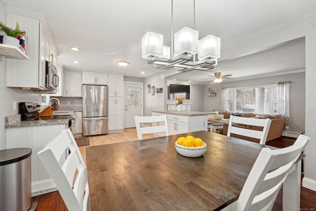dining room with light wood-type flooring, recessed lighting, a ceiling fan, a baseboard radiator, and a chandelier