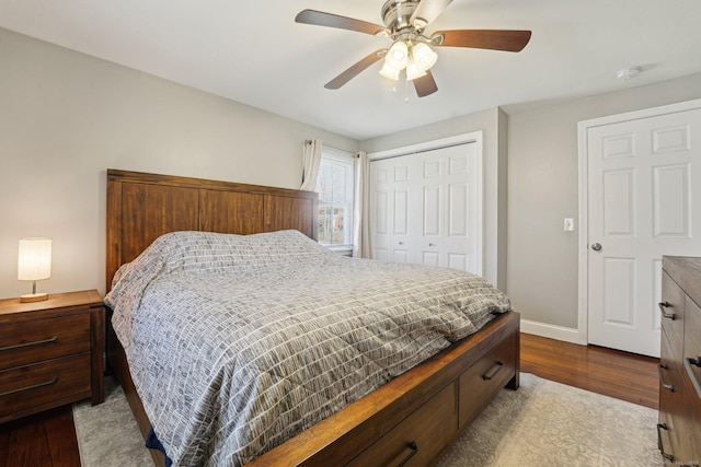 bedroom with dark wood-style flooring, a closet, baseboards, and a ceiling fan