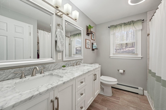 full bathroom with a baseboard heating unit, toilet, double vanity, and baseboards