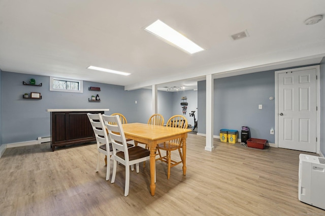 dining space featuring a baseboard radiator, light wood-type flooring, and baseboards