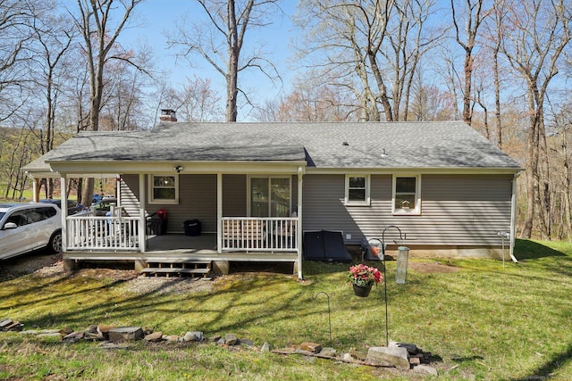 back of property featuring a chimney, a yard, a wooden deck, and roof with shingles