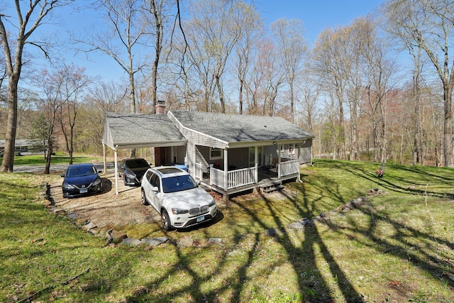 view of side of property with a carport, roof with shingles, a chimney, a lawn, and a porch