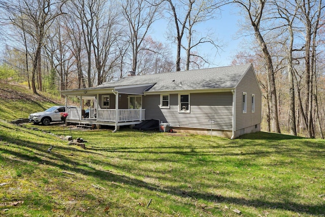back of property featuring a deck, a lawn, a chimney, and roof with shingles