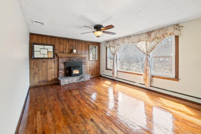 unfurnished living room featuring visible vents, a healthy amount of sunlight, a ceiling fan, and hardwood / wood-style floors