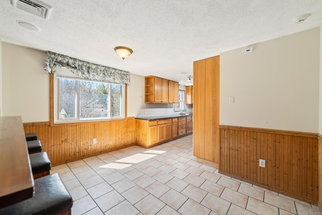 kitchen with open shelves, visible vents, wood walls, and wainscoting