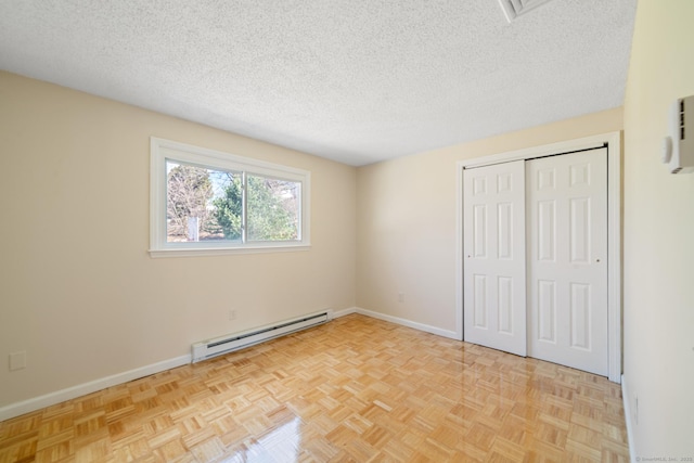 unfurnished bedroom with a closet, baseboard heating, a textured ceiling, and baseboards