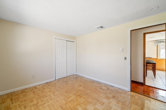 unfurnished bedroom with visible vents, baseboards, a textured ceiling, and a closet