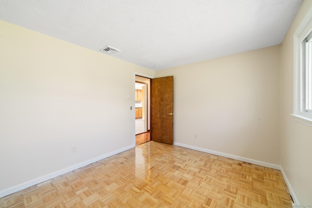spare room featuring visible vents, baseboards, and a textured ceiling