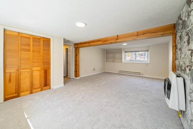 below grade area with a textured ceiling, heating unit, baseboard heating, and carpet floors