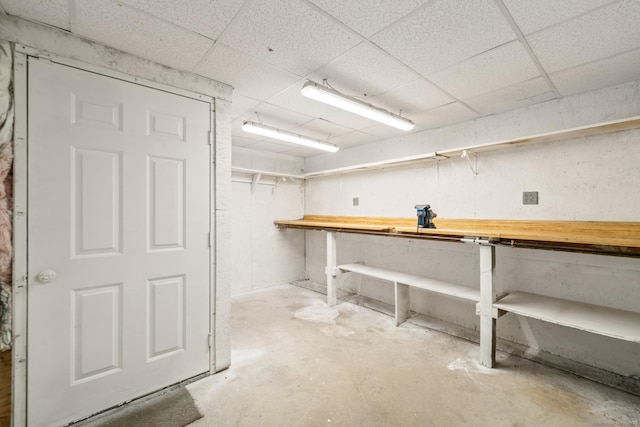 basement with a drop ceiling and a workshop area