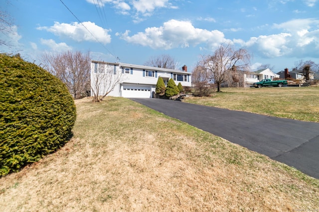 view of front of property with a garage, a front yard, a chimney, and driveway