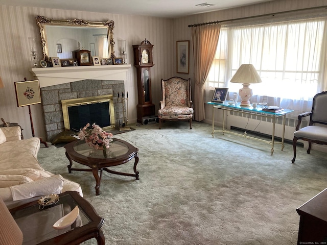 carpeted living area with a stone fireplace and radiator heating unit