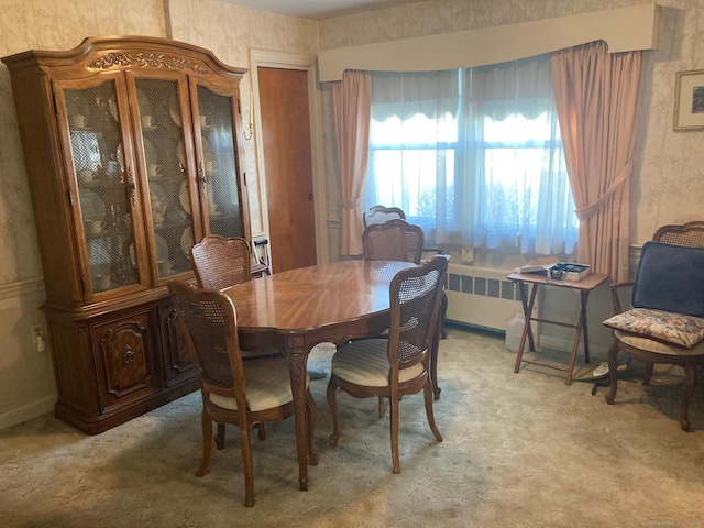 dining area featuring baseboards, light colored carpet, radiator heating unit, and wallpapered walls