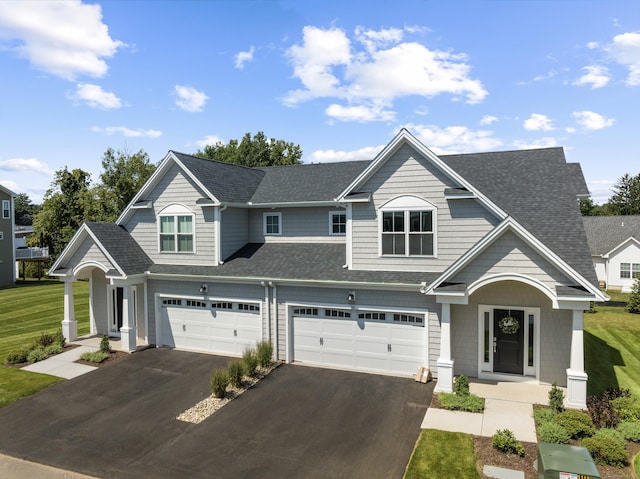 view of front of house with a front lawn, roof with shingles, a garage, and aphalt driveway