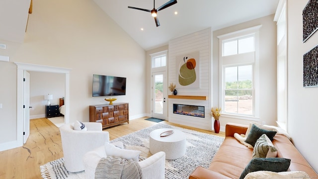 living area with ceiling fan, high vaulted ceiling, wood finished floors, and plenty of natural light