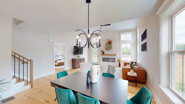 dining space with light wood-style flooring, visible vents, a chandelier, baseboards, and stairway