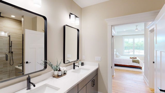 ensuite bathroom featuring a sink, a shower stall, wood finished floors, ceiling fan, and double vanity