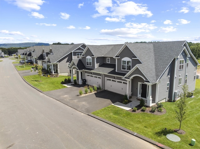 view of front of property featuring a front yard, aphalt driveway, a residential view, a shingled roof, and a garage