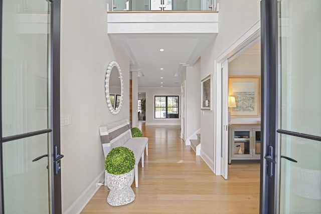 hallway featuring baseboards, stairs, recessed lighting, and light wood-style floors