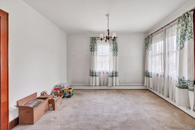 interior space with an inviting chandelier, carpet floors, a wealth of natural light, and baseboard heating