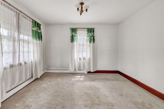 spare room featuring baseboards, a notable chandelier, baseboard heating, and carpet