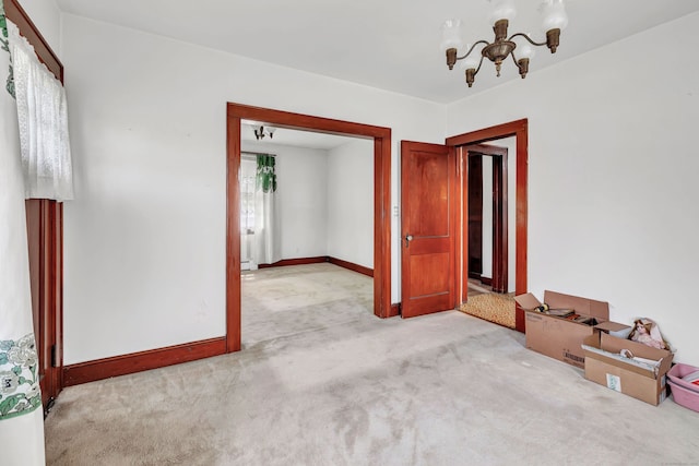 spare room with baseboards, carpet, and a chandelier