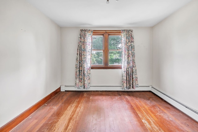 unfurnished room featuring baseboards, baseboard heating, and hardwood / wood-style flooring