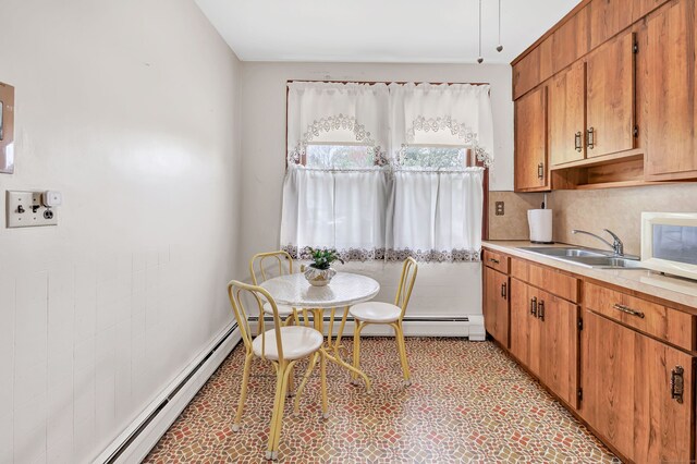 kitchen with a sink, light countertops, white microwave, and brown cabinets