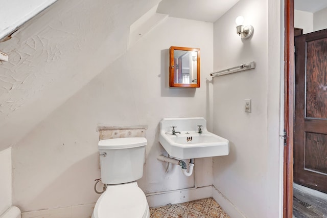 half bathroom featuring baseboards, a sink, lofted ceiling, and toilet