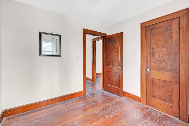 unfurnished room featuring baseboards and wood-type flooring