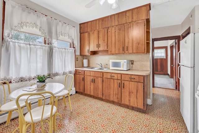 kitchen with a sink, white appliances, light countertops, a ceiling fan, and decorative backsplash