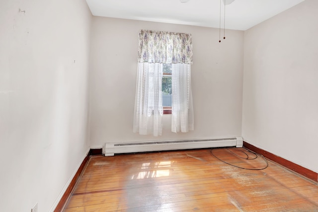 empty room featuring baseboards, baseboard heating, and hardwood / wood-style flooring