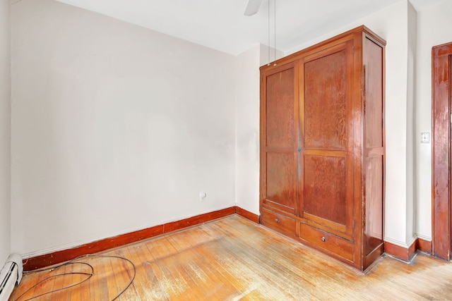 unfurnished bedroom with baseboards, ceiling fan, baseboard heating, and light wood-style floors