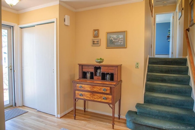 foyer entrance with baseboards, ornamental molding, wood finished floors, and stairway