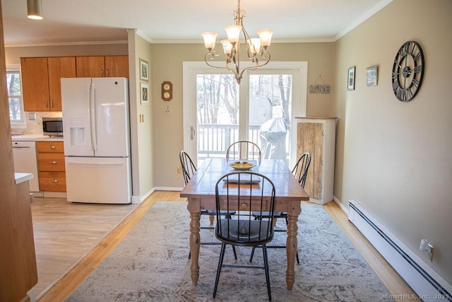 dining area featuring light wood-style floors, baseboard heating, a notable chandelier, and a healthy amount of sunlight