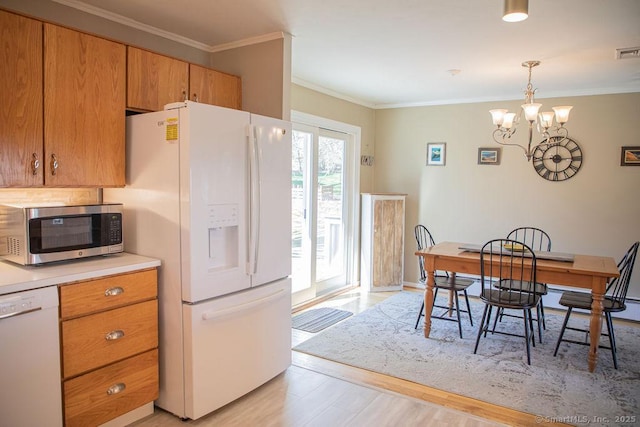 kitchen featuring crown molding, white appliances, light countertops, light wood-style flooring, and a notable chandelier