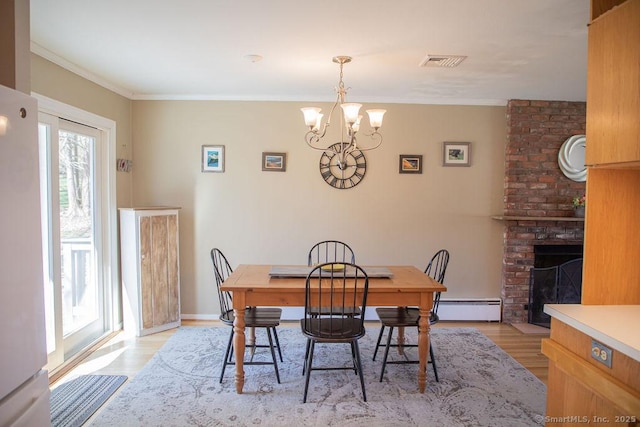 dining area featuring visible vents, a brick fireplace, a baseboard heating unit, light wood finished floors, and a notable chandelier
