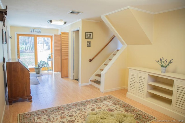 foyer entrance with visible vents, crown molding, stairway, baseboards, and light wood-style floors