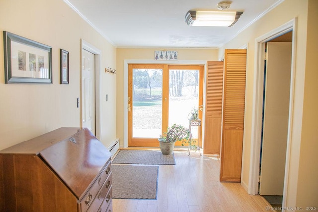 entryway featuring a baseboard heating unit, ornamental molding, and light wood finished floors