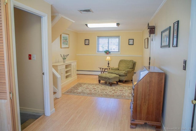 sitting room with visible vents, ornamental molding, a baseboard heating unit, and wood finished floors