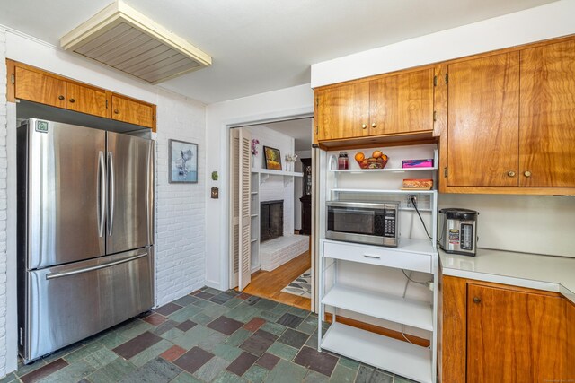 127 Separatist Rd, Mansfield, CT 06268 - kitchen with appliances with stainless steel finishes, open shelves, brick wall, light countertops, and brown cabinetry