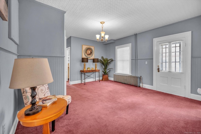 carpeted foyer entrance featuring an inviting chandelier, radiator heating unit, and a textured ceiling
