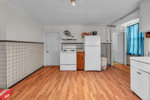 kitchen featuring white appliances, light wood-style floors, under cabinet range hood, wainscoting, and tile walls